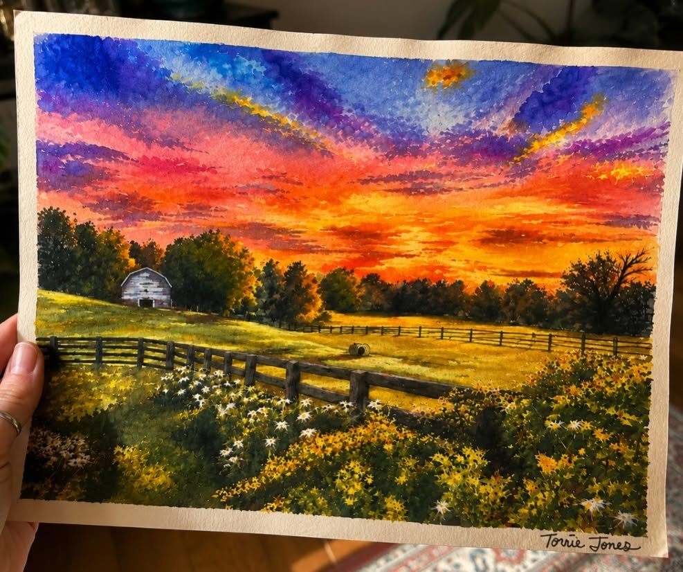 Watercolor painting of a barn and pasture under a vivid sunset